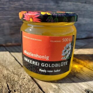 Akazienhonig im Glas vor einem Bienenkasten